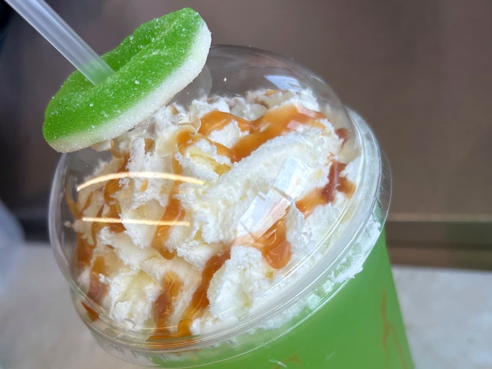 Caramel apple specialty lemonade topped with whipped cream, caramel drizzle and a green apple candy