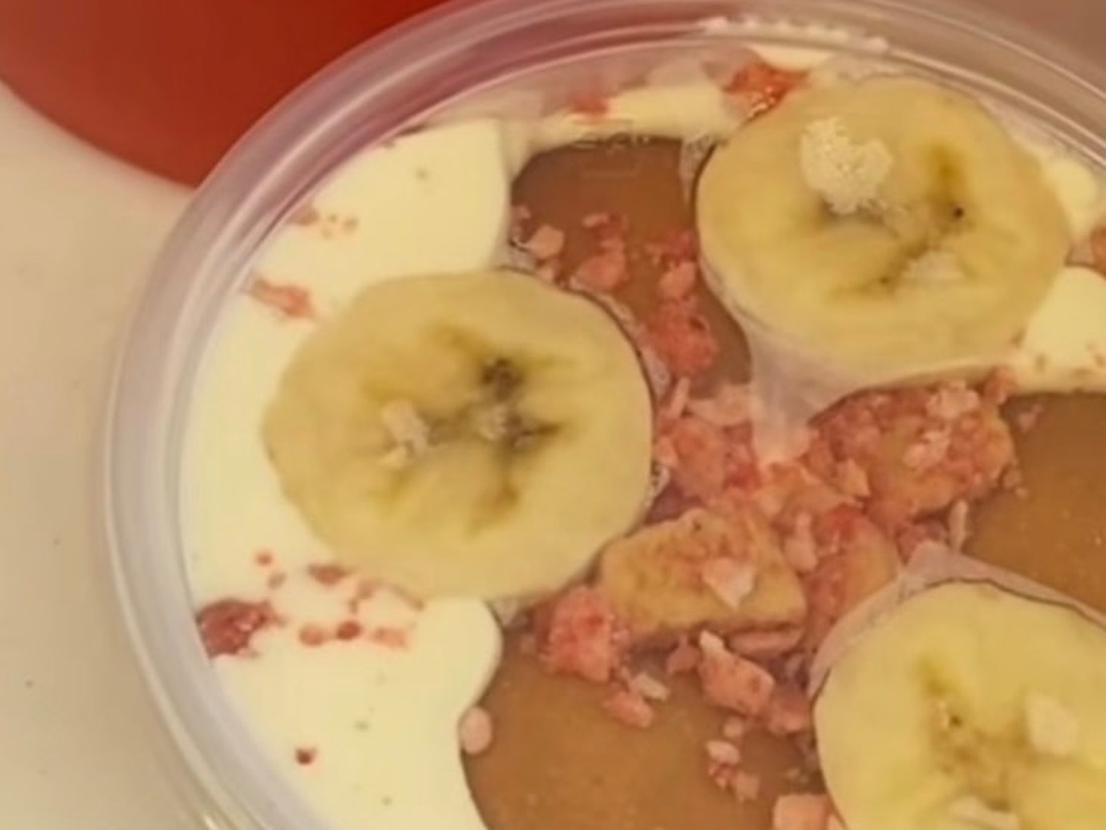Homemade banana pudding topped with banana slices and strawberry crumble beside a strawberry lemonade